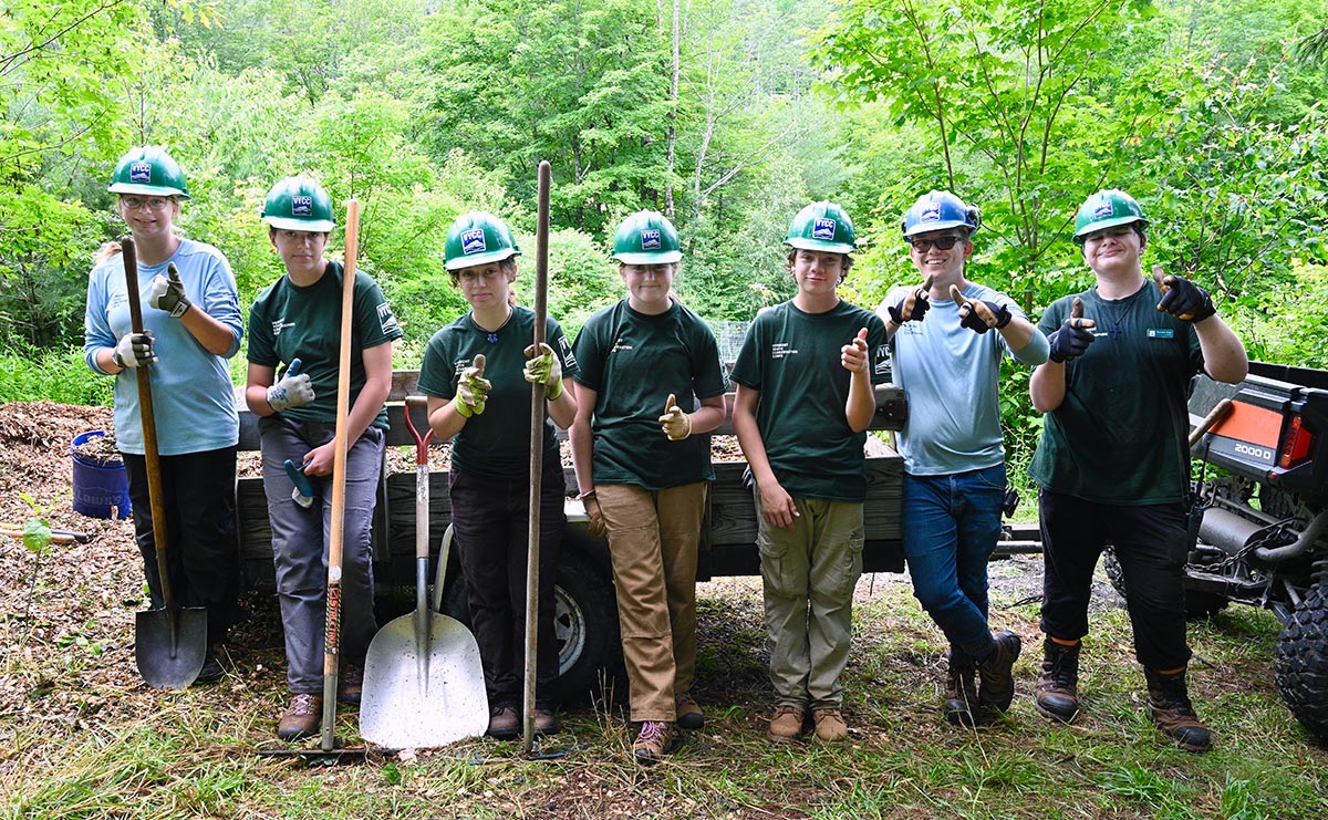 The Woodstock Conservation Crew poses for a photo, holding tools and offering thumbs up.